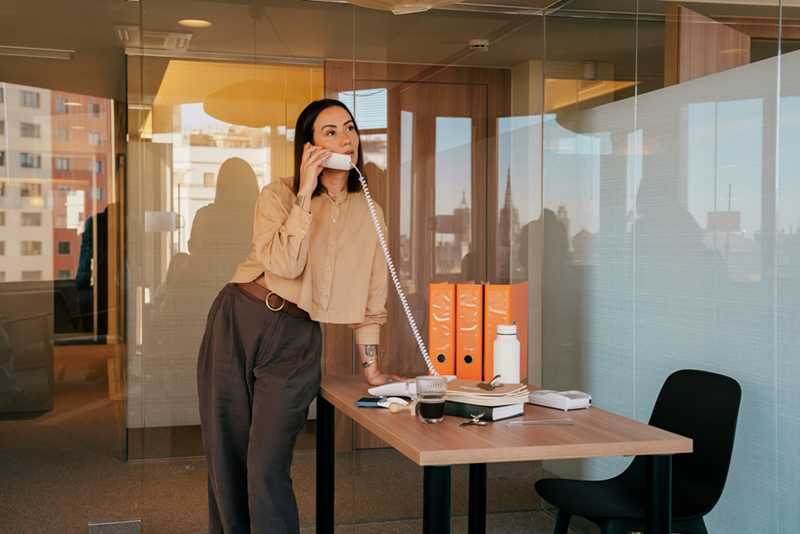 A female employee answers the phone in an office environment.