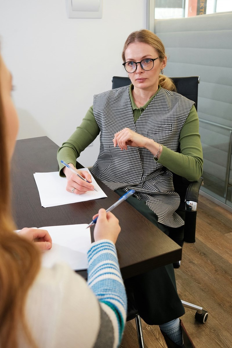 Woman sitting down in an office interviewing another woman.