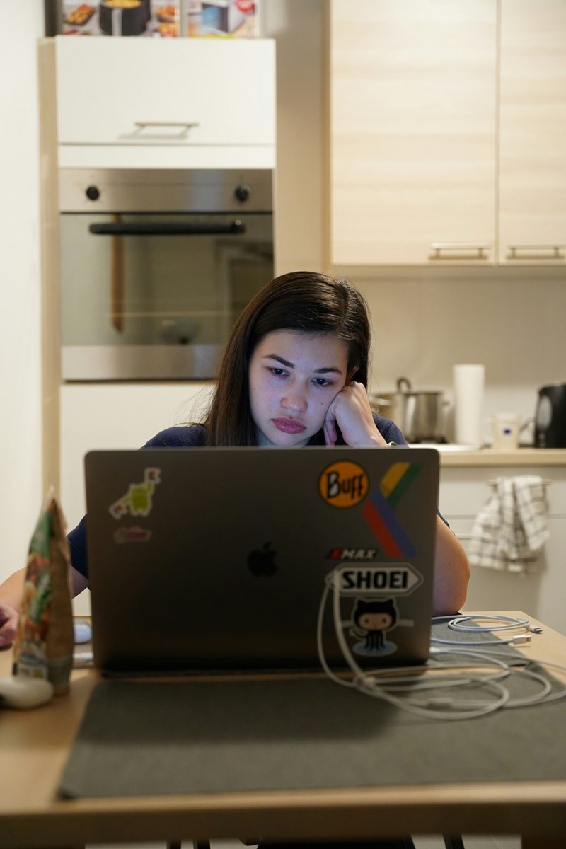 Frustrated woman sitting down in her kitchen looking at her computer.