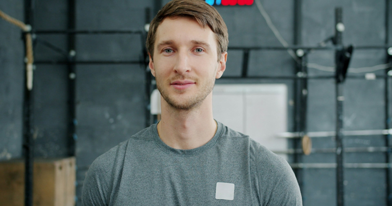 Close-up of a man standing in front of pull-up bars in the gym