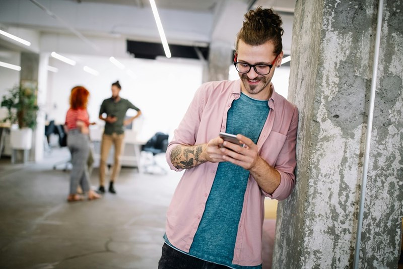 Man grins while typing up message to coworker.