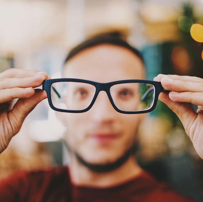 Man holds up a pair of glasses.