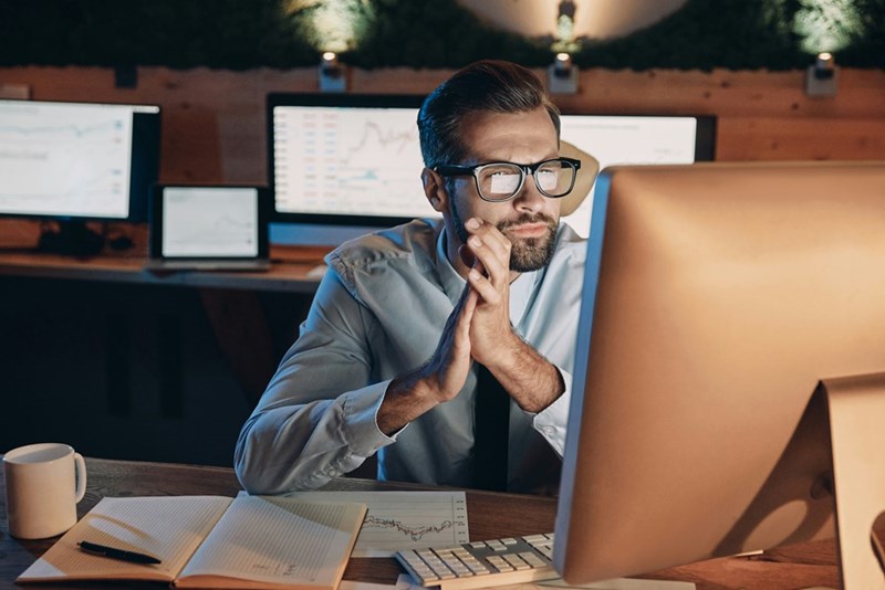 A male employee claps his hands while on a video call at work.
