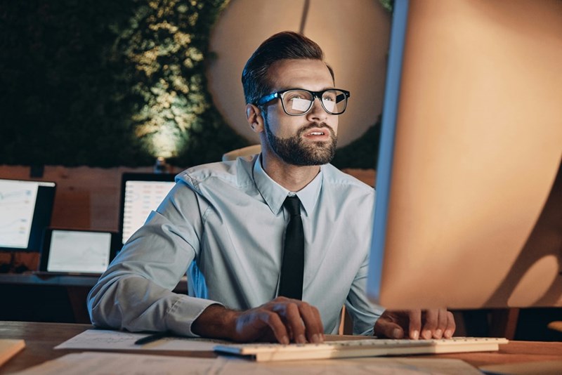 A male employee types on his keyboard in a confined office space.