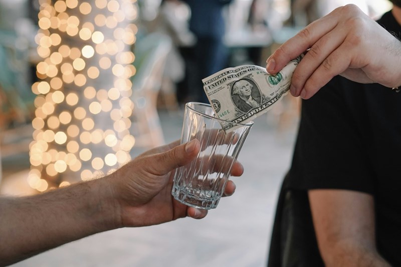 A customer puts a tip into a tip jar.