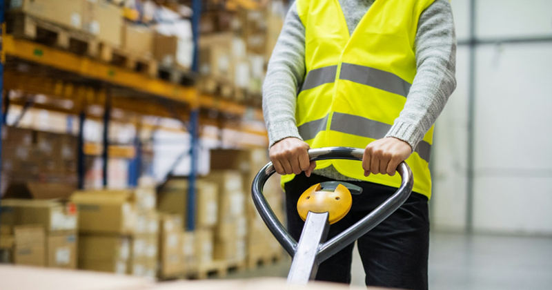 Close-up of a man in hi vis pulling a pallet in a warehouse