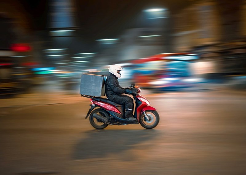 A delivery motorbike speeds past on a busy street