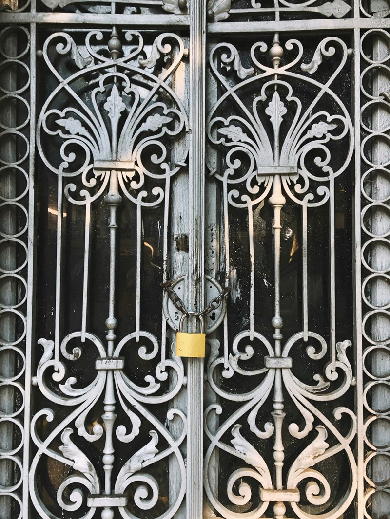 A fancy iron gate to an expensive home is chain-locked