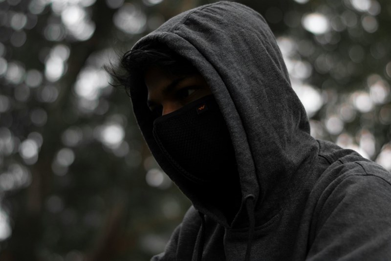 A man with a black hoodie on covering his face