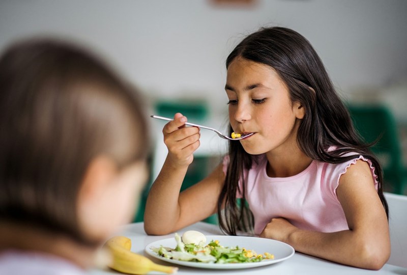 Little girl picks at her food.