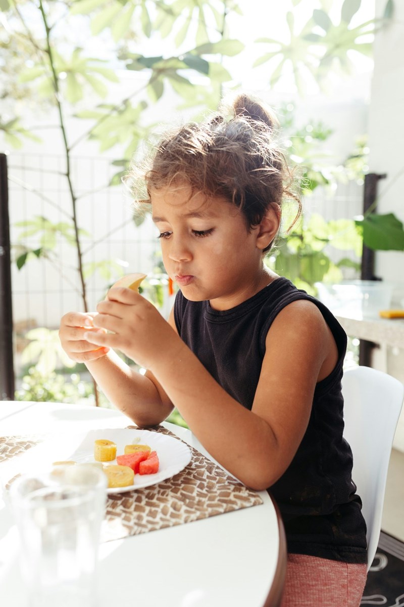 Little girl eats a plate of food.
