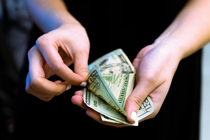 Homeowner holds bills and counts them out, preparing to pay for an HOA fine.