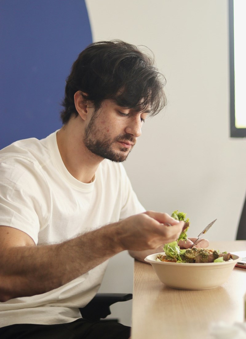 Tired worker eats a salad as his office lunch.