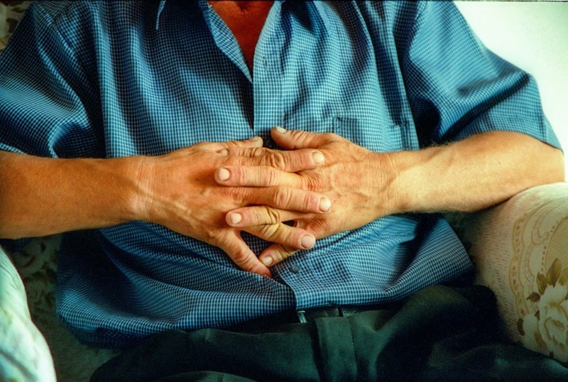 Old man sitting on a couch with crossed hands on his chest.