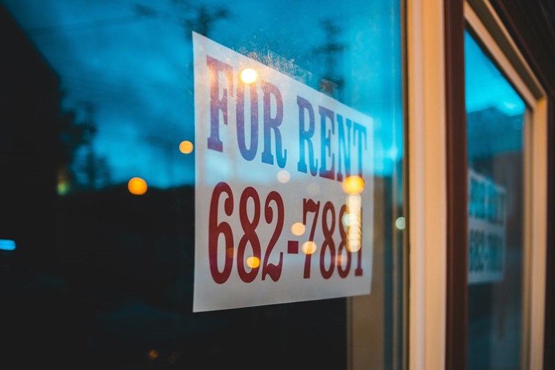 A “For Rent” sign is posted against a glass window.