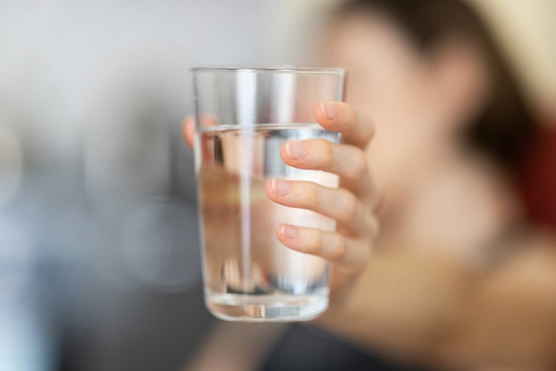 Person holding clear drinking glass