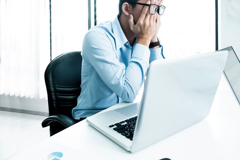 A frustrated man sits with his head in his hands