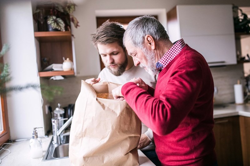 Grandfather and caretaker unpack groceries.