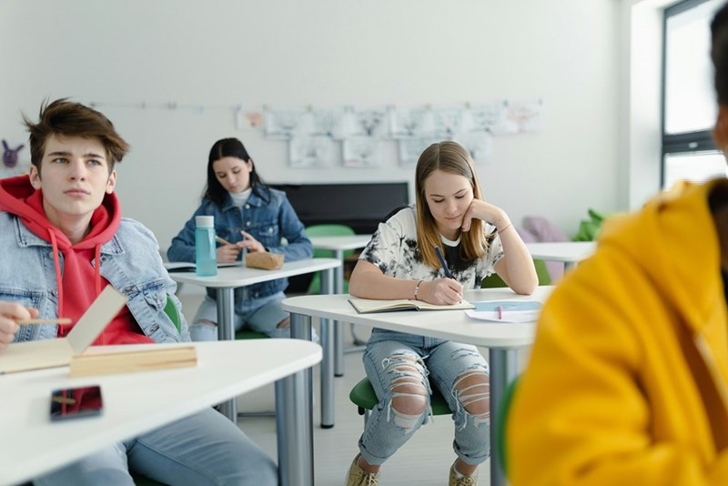 High school students paying attention in class, sitting in their desks and writing notes
