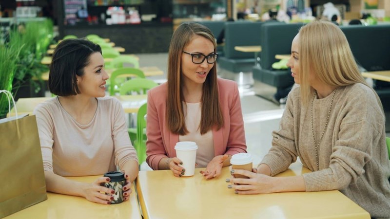 Three women talking at a cafe with drinks