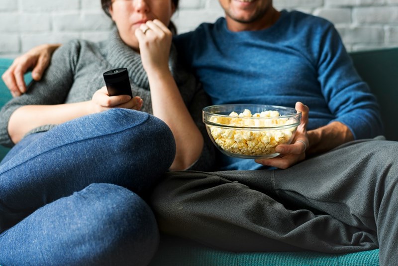 A couple watches television together on the couch