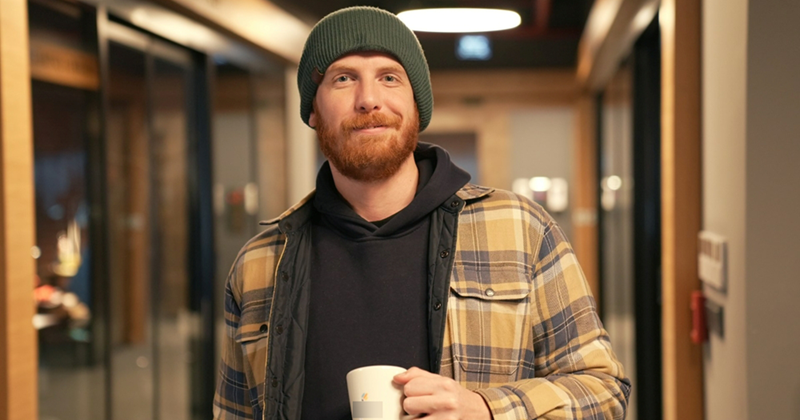 A man holding a cup of coffee in an office hallway