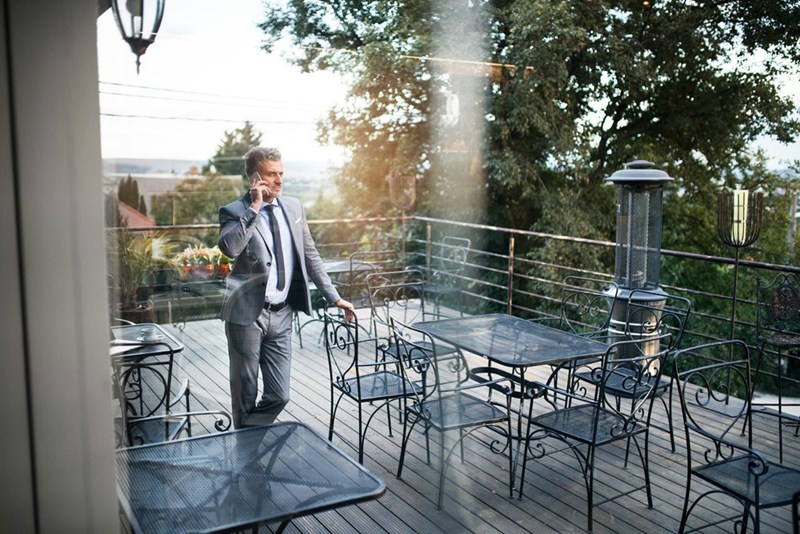 Business man makes call from hotel patio, realizing he's lost the job.