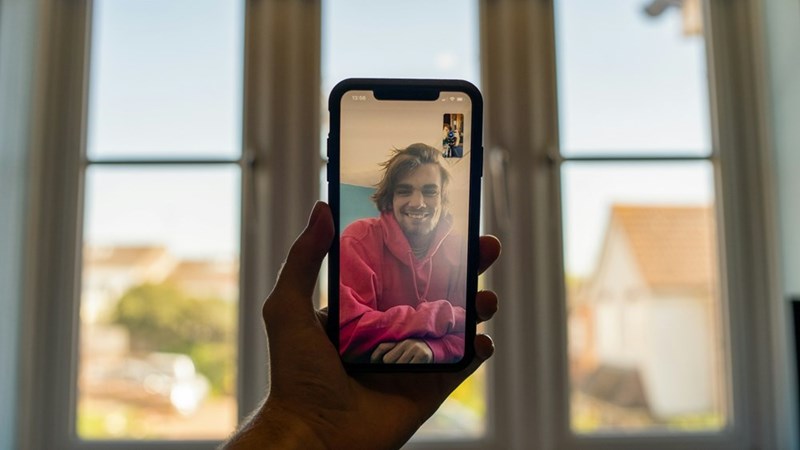 Person holding a smartphone during a FaceTime video call.