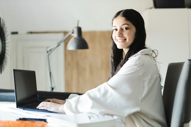 Young employee smiling while working remotely on a laptop