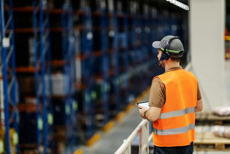 A boss with a tablet oversees shipping at a warehouse