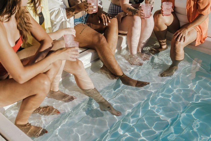 Friends relaxing with cocktails at a stylish pool gathering, capturing the calm and social atmosphere of an adults-only party.