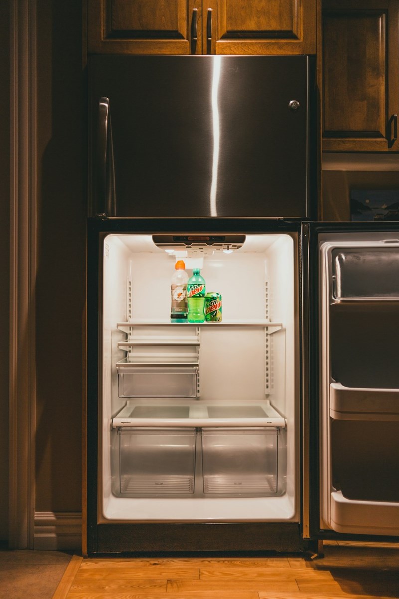 Nearly empty dorm fridge with forgotten drinks inside, representing college move-out mistakes and shared roommate responsibilities.
