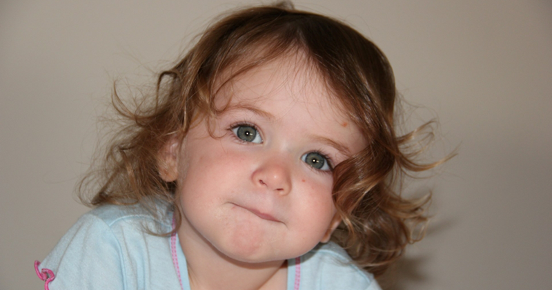 Close-up of a young girl against a plain background