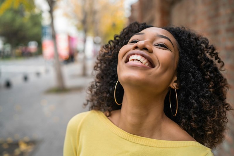 Portrait of beautiful young confident woman laughing in the street outside