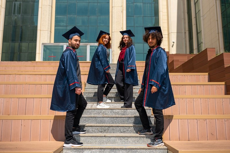 High school students stand on the steps at their graduation.