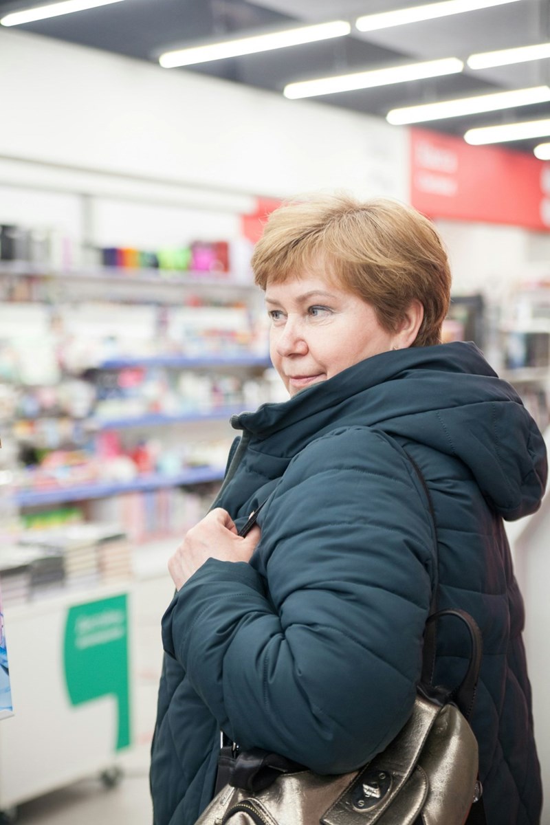 A portrait of an older woman in a coat, looking mischievous.