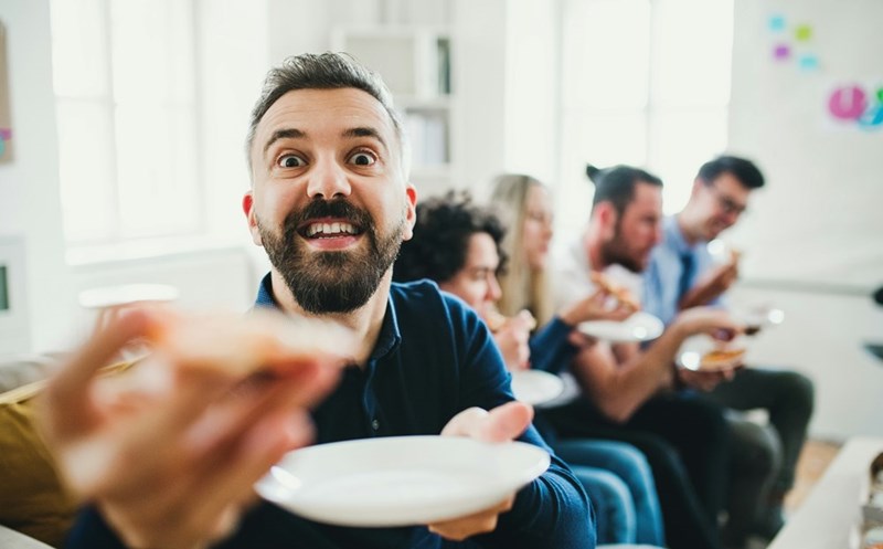 A group of young coworkers sit together at a lunch table