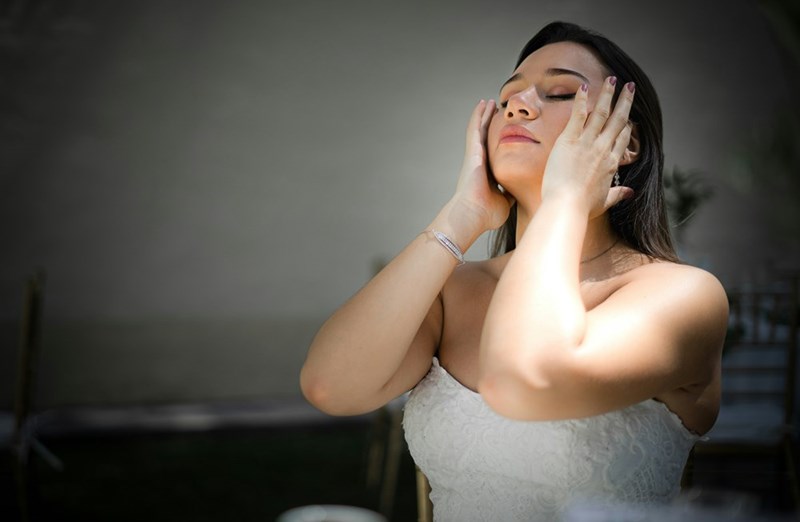A woman in a white dress massages her temples