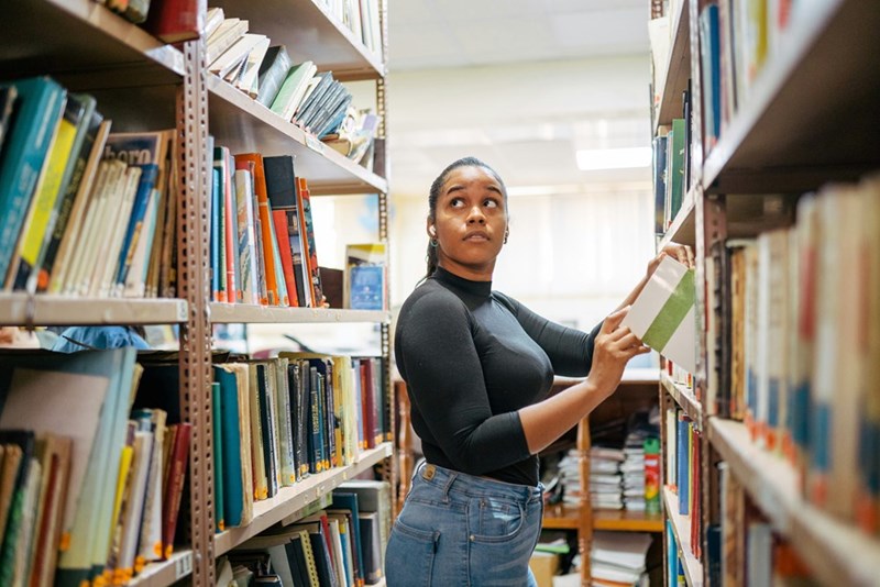 A woman standing in a library holding a book