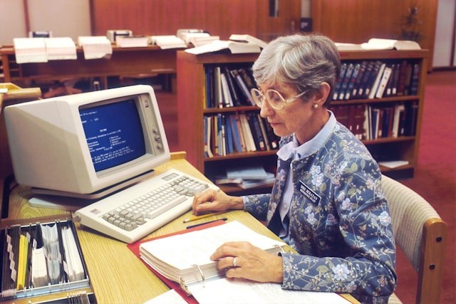 A woman sitting at a desk with a desktop computer