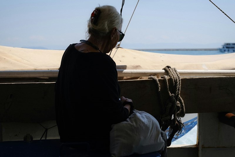 Old woman sitting down on a boat in the shadow.