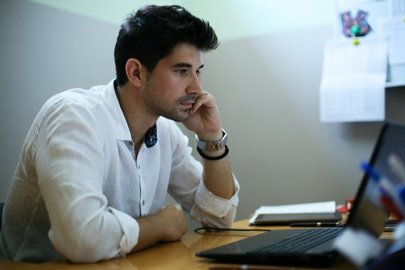 A young man works on a laptop in his office