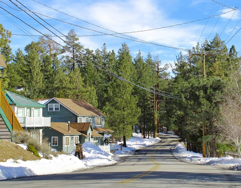A dead end street with houses, trees and snow.