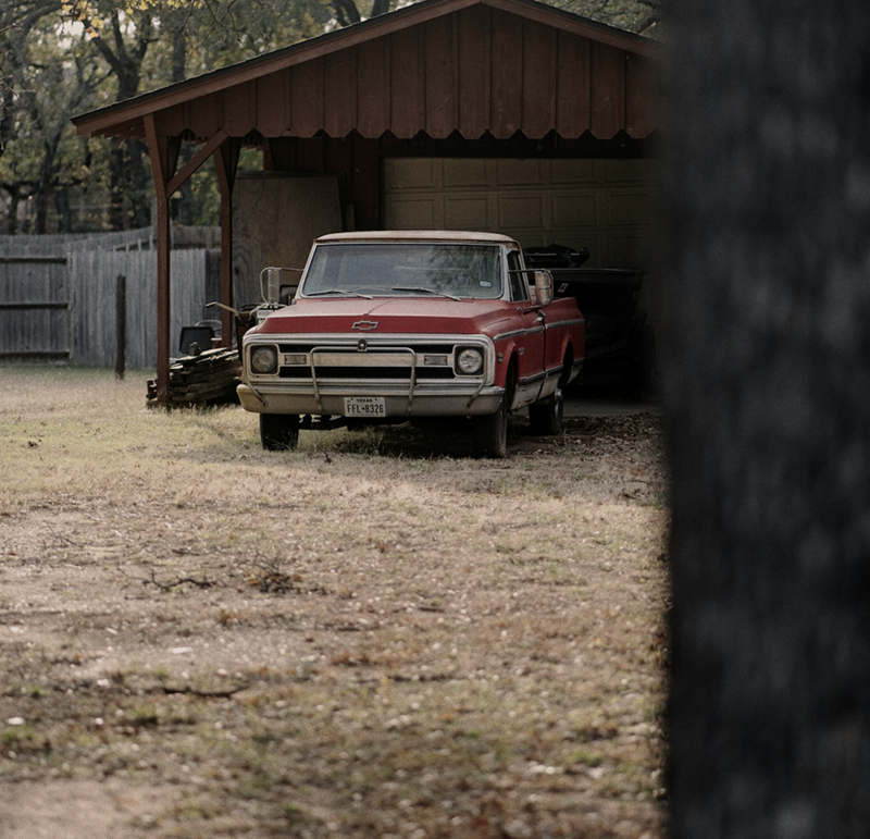An old red truck parked out back in a shed.