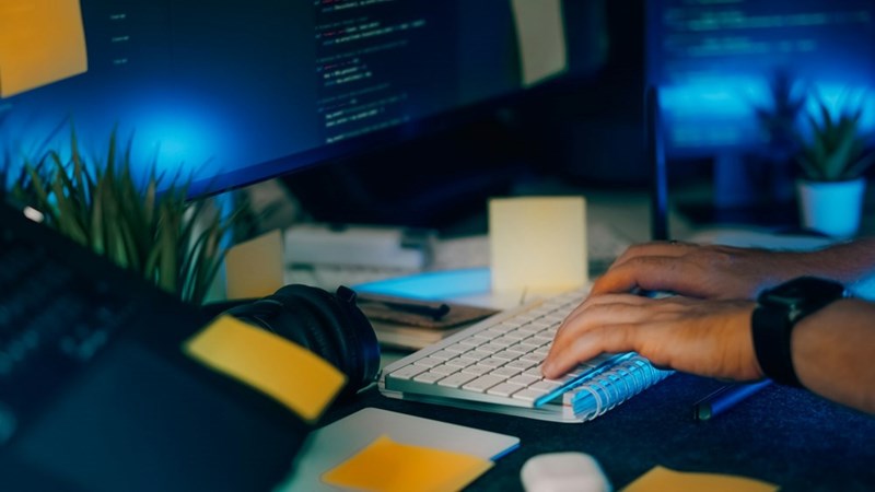 Software developer using AI coding tools and automation technology during late-night programming session.