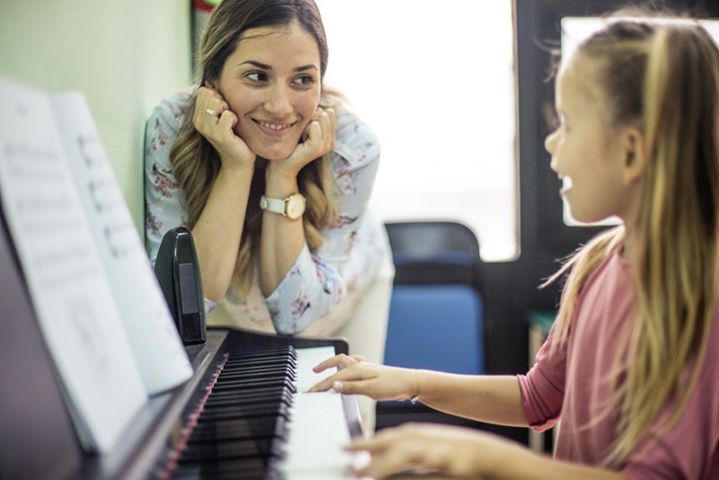 Woman looking at a girl playing the piano