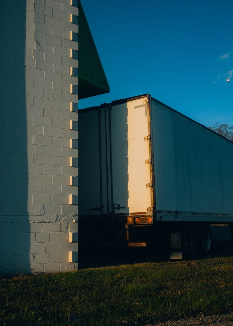 The back of a large truck backs into a storage area to drop off its load