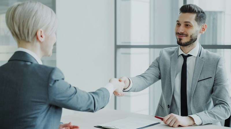 A Human Resources representative shakes hands with her male employee.