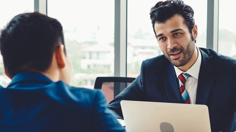 A manager speaks candidly with his male employee in a private meeting.
