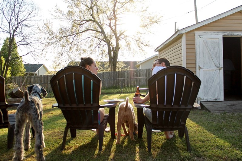 A man and woman are sitting in lawn chairs in the backyard of their new neighborhood.